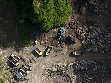 Aerial view of Tambang Pasir Merapi Kali Gendol Sand Mine with excavators loading sand into trucks near large rocks Kecamatan Cangkringan Daerah Istimewa Yogyakarta Indonesia. Aerial view of Tambang Pasir Merapi Kali Gendol Sand Mine with excavators loading sand into trucks near large rocks Kecamatan Cangkringan Daerah Istimewa Yogyakarta Indonesia.