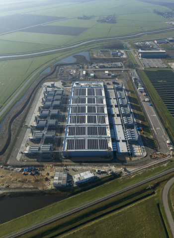 Aerial view of an AI data center with cooling towers and cloud computing hub exterior surrounded by green fields and canals. Aerial view of an AI data center with cooling towers and cloud computing hub exterior surrounded by green fields and canals.