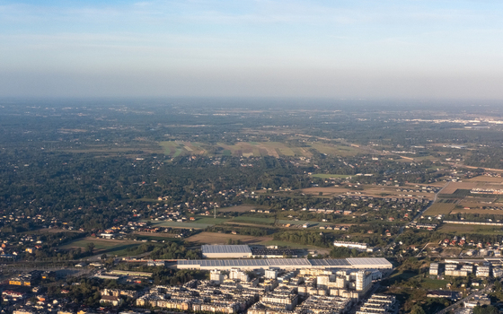 Aerial view of sprawling urban development meeting the verdant expanse of forests and fields under a soft diffused sky Warsaw Masovian Voivodeship Poland. Aerial view of sprawling urban development meeting the verdant expanse of forests and fields under a soft diffused sky Warsaw Masovian Voivodeship Poland.