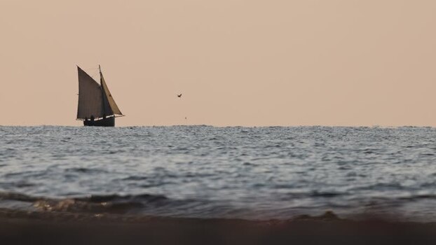 View of a sailboat silhouetted on the sea horizon France. View of a sailboat silhouetted on the sea horizon France.