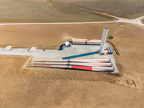 Aerial view of a wind turbine construction site featuring large blades and a tower section on dry farmland in Swellendam Western Cape South Africa. Aerial view of a wind turbine construction site featuring large blades and a tower section on dry farmland in Swellendam Western Cape South Africa.