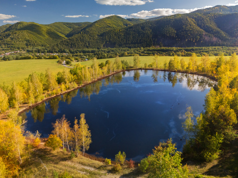 Aerial view of the Gudronove jamy acid tar lagoons surrounded by autumn trees with the Low Tatras mountains in the background in Predajna Banskobystricky kraj Slovakia. Aerial view of the Gudronove jamy acid tar lagoons surrounded by autumn trees with the Low Tatras mountains in the background in Predajna Banskobystricky kraj Slovakia.