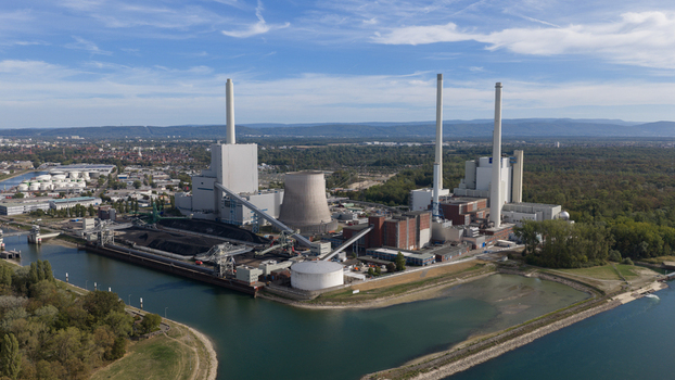 Aerial view of Rheinhafen power station with its tall chimneys cooling tower and coal storage facilities situated along the riverbank in Karlsruhe Baden Wurttemberg Germany.