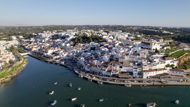 Aerial view of the coastal town of Ferragudo featuring white washed buildings a historic church and small fishing boats along the waterfront in Ferragudo Faro District Portugal.