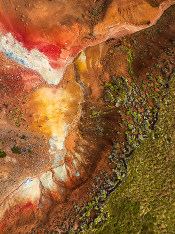 Aerial view of vibrant geothermal landscape featuring colorful mineral deposits steaming vents and patches of green mossy terrain in Iceland. Aerial view of vibrant geothermal landscape featuring colorful mineral deposits steaming vents and patches of green mossy terrain in Iceland.