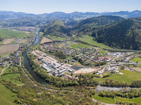 Aerial view of the Orava river winding past an industrial facility and the village surrounded by lush green hills under a clear sky Oravsky Podzamok Zilina Region Slovakia. Aerial view of the Orava river winding past an industrial facility and the village surrounded by lush green hills under a clear sky Oravsky Podzamok Zilina Region Slovakia.