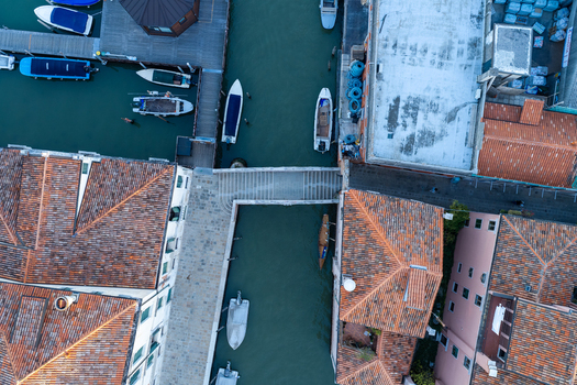 Aerial view of the historic canals and terracotta rooftops of Venice featuring a stone bridge crossing the water with moored boats Venice Veneto Italy. Aerial view of the historic canals and terracotta rooftops of Venice featuring a stone bridge crossing the water with moored boats Venice Veneto Italy.