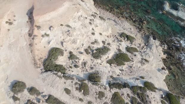 Aerial view of rocky coastline and turquoise sea in Cyprus.