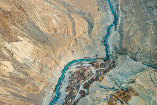 Aerial view of a turquoise river carving through the rugged textured landscape of Chapursan Valley creating a mesmerizing contrast of colors and forms Hunza Nagar Pakistan. Aerial view of a turquoise river carving through the rugged textured landscape of Chapursan Valley creating a mesmerizing contrast of colors and forms Hunza Nagar Pakistan.