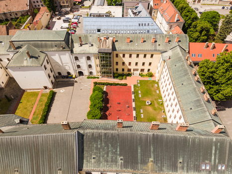 Aerial view of a historic building complex featuring a courtyard with a red sports court and green metal roofs in Trnava Trnava Region Slovakia. Aerial view of a historic building complex featuring a courtyard with a red sports court and green metal roofs in Trnava Trnava Region Slovakia.