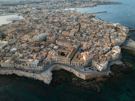 Aerial view of the Island of Ortigia featuring historic stone buildings and a rocky coastline along the Mediterranean Sea Syracuse Sicily Italy. Aerial view of the Island of Ortigia featuring historic stone buildings and a rocky coastline along the Mediterranean Sea Syracuse Sicily Italy.