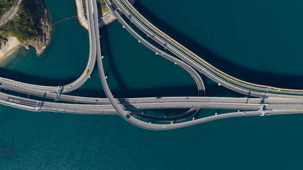 Aerial view of a complex highway interchange and bridge system with cars driving over deep blue water along the coast in Hong Kong Hong Kong.