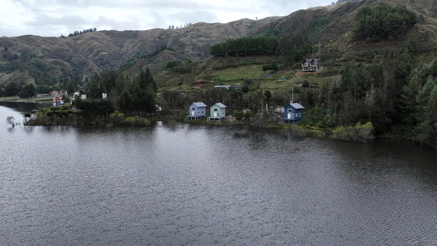 Aerial view of Corani Lake with small colorful houses on the shore surrounded by rolling hills and trees in Chapare Cochabamba Department Bolivia. Aerial view of Corani Lake with small colorful houses on the shore surrounded by rolling hills and trees in Chapare Cochabamba Department Bolivia.