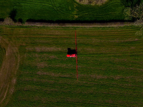 Aerial view of a red agricultural sprayer machine working in a green field at Gnosall Heath in Gnosall England United Kingdom. Aerial view of a red agricultural sprayer machine working in a green field at Gnosall Heath in Gnosall England United Kingdom.