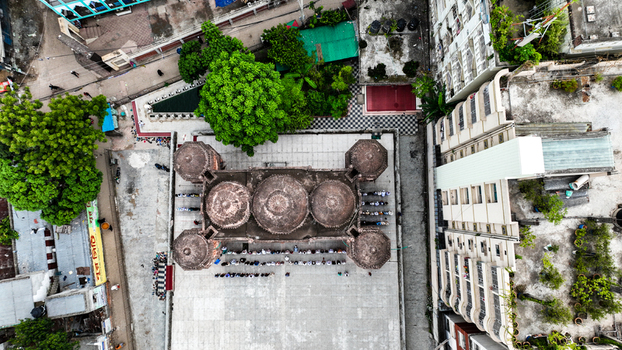Aerial view of the historic Khan Mohammad Mridha Mosque with its distinctive domes and courtyard surrounded by urban buildings and lush trees in Dhaka Dhaka Division Bangladesh. Aerial view of the historic Khan Mohammad Mridha Mosque with its distinctive domes and courtyard surrounded by urban buildings and lush trees in Dhaka Dhaka Division Bangladesh.