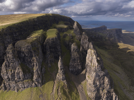 Aerial view of the Old Man of Storr rock formations on the Isle of Skye featuring rugged cliffs grassy slopes and the sea in the background Scotland United Kingdom. Aerial view of the Old Man of Storr rock formations on the Isle of Skye featuring rugged cliffs grassy slopes and the sea in the background Scotland United Kingdom.