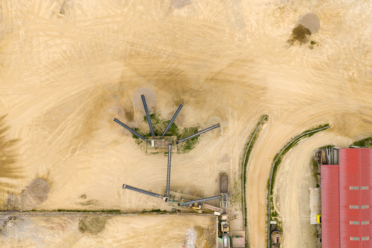 Aerial view of an industrial quarry site featuring conveyor belts sand piles and tire tracks on the ground San Giovanni Valdarno Tuscany Italy.