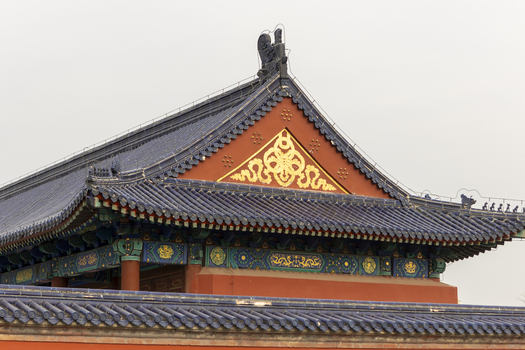View of the ornate blue tiled roof of a traditional Chinese temple with golden decorative patterns and intricate carvings in Beijing Beijing China. View of the ornate blue tiled roof of a traditional Chinese temple with golden decorative patterns and intricate carvings in Beijing Beijing China.