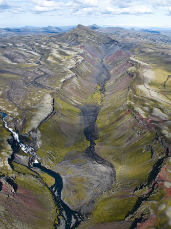 Aerial view of Eldgja volcanic canyon featuring dramatic red and green slopes a winding river and cascading waterfalls in Kirkjubaejarklaustur Skaftarhreppur Iceland. Aerial view of Eldgja volcanic canyon featuring dramatic red and green slopes a winding river and cascading waterfalls in Kirkjubaejarklaustur Skaftarhreppur Iceland.