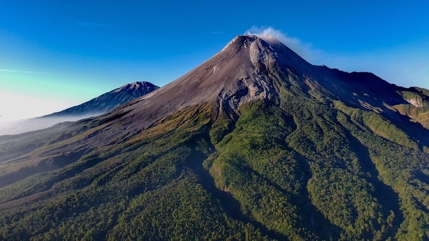 Aerial view of Mount Merapi with its volcanic peak rocky slopes and surrounding lush green forests in Kecamatan Pakem Daerah Istimewa Yogyakarta Indonesia.