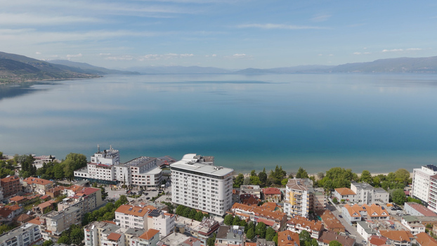 Aerial view of the town of Pogradec with its modern buildings and traditional red tiled roofs situated along the calm blue shores of Lake Ohrid in Pogradec Korce County Albania. Aerial view of the town of Pogradec with its modern buildings and traditional red tiled roofs situated along the calm blue shores of Lake Ohrid in Pogradec Korce County Albania.