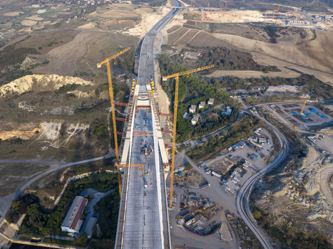 Aerial view of a large suspension bridge under construction with tall yellow cranes and concrete pillars set within a hilly landscape in Istanbul Istanbul Turkiye.