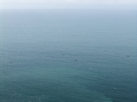 Aerial view of a vast expanse of turquoise ocean fading into a hazy horizon with tiny boats dotting the surface Gunungkidul Regency Indonesia. Aerial view of a vast expanse of turquoise ocean fading into a hazy horizon with tiny boats dotting the surface Gunungkidul Regency Indonesia.
