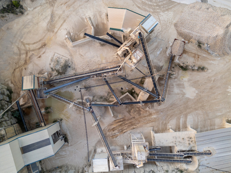Aerial view of a stone quarry with industrial crushing machinery conveyor belts and piles of gravel in the dusty terrain of Teulada Valencian Community Spain.