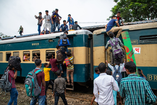 Dhaka Bangladesh 14 June 2018 View of crowds of people climbing onto a train and sitting on the roof at Airport Railway Station during the Eid al Fitr holiday rush. Dhaka Bangladesh 14 June 2018 View of crowds of people climbing onto a train and sitting on the roof at Airport Railway Station during the Eid al Fitr holiday rush.