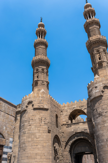 View of Bab Zuwayla the historic medieval gate with its two towering ornate minarets and massive stone walls under a clear blue sky El Darb El Ahmar Cairo Governorate Egypt. View of Bab Zuwayla the historic medieval gate with its two towering ornate minarets and massive stone walls under a clear blue sky El Darb El Ahmar Cairo Governorate Egypt.