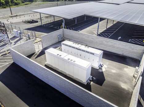 Aerial view of Tesla Megapack battery storage units at Six Flags Magic Mountain next to a solar panel canopy Los Angeles County California United States. Aerial view of Tesla Megapack battery storage units at Six Flags Magic Mountain next to a solar panel canopy Los Angeles County California United States.