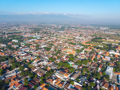 Aerial view of the urban landscape featuring dense residential rooftops scattered green trees and local infrastructure in Probolinggo East Java Indonesia.