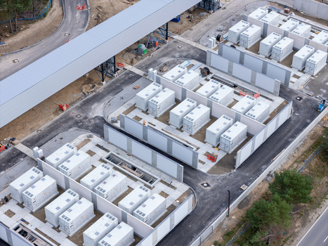 Aerial view of a battery energy storage system with rows of white containerized units concrete partitions and paved access paths in Poland.
