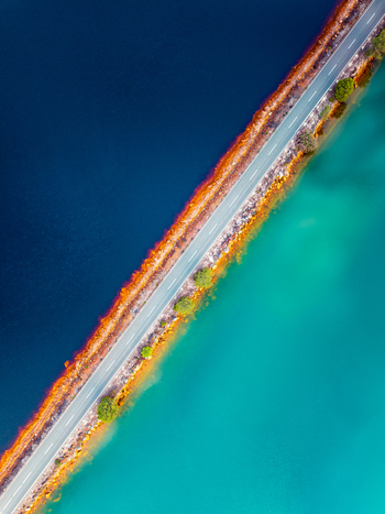 Aerial view of a road crossing the vibrant red and turquoise waters of tailing ponds with sparse vegetation along the banks in Andalusia Spain. Aerial view of a road crossing the vibrant red and turquoise waters of tailing ponds with sparse vegetation along the banks in Andalusia Spain.