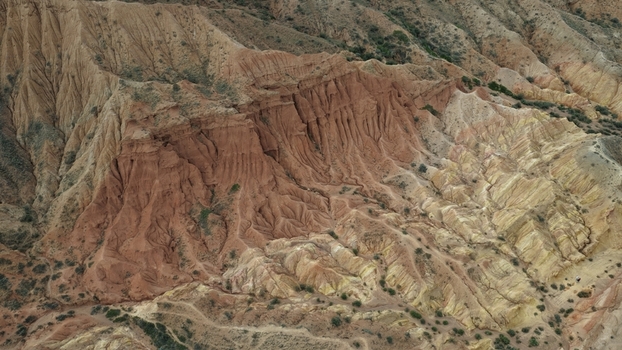 Aerial view of the Jety Oguz rock formations featuring dramatic red sandstone cliffs deep erosion gullies and rugged terrain in Jety Oguz Issyk Kul Region Kyrgyzstan. Aerial view of the Jety Oguz rock formations featuring dramatic red sandstone cliffs deep erosion gullies and rugged terrain in Jety Oguz Issyk Kul Region Kyrgyzstan.