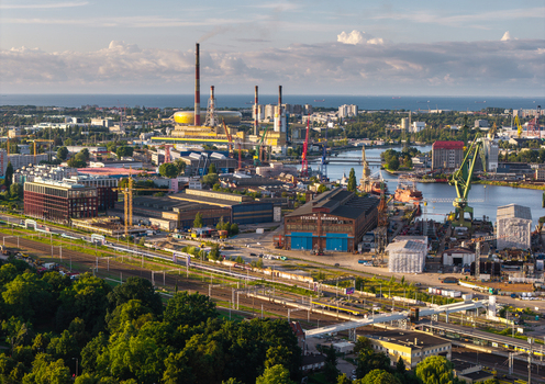 Aerial view of the historic Gdansk Shipyard with its iconic cranes industrial buildings and railway tracks under a clear sky in Gdansk Pomeranian Voivodeship Poland. Aerial view of the historic Gdansk Shipyard with its iconic cranes industrial buildings and railway tracks under a clear sky in Gdansk Pomeranian Voivodeship Poland.