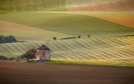 View of Windmill Kunkovice standing among the rolling agricultural hills and green fields under soft light in Kunkovice Zlin Region Czechia. View of Windmill Kunkovice standing among the rolling agricultural hills and green fields under soft light in Kunkovice Zlin Region Czechia.