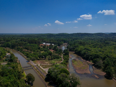 Aerial view of a river flowing through a lush tropical landscape with dense green forests a canal and clear blue sky in Indonesia. Aerial view of a river flowing through a lush tropical landscape with dense green forests a canal and clear blue sky in Indonesia.