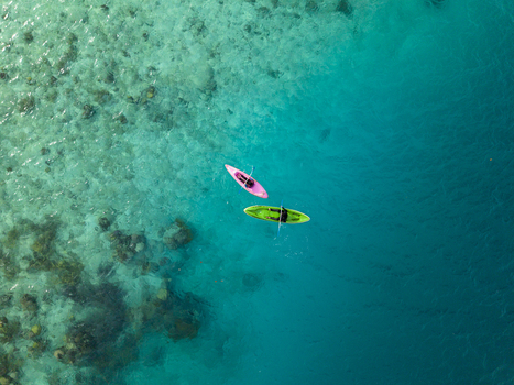 Aerial view of two kayaks one pink and one green floating in the crystal clear turquoise waters near Menjangan Kecil Island Karimunjawa Jawa Tengah Indonesia.