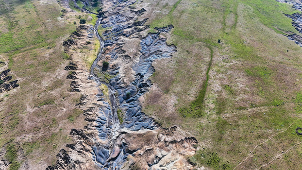 Aerial view of severe soil erosion and deep gullies cutting through the green and brown landscape Pietermaritzburg KwaZulu Natal South Africa.