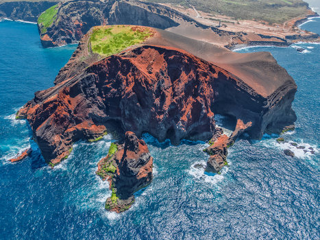 Aerial view of the dramatic Capelinhos Volcano where rust colored cliffs meet the deep blue sea a stunning contrast of volcanic rock and ocean waves Capelo A&ccedil;ores Portugal.