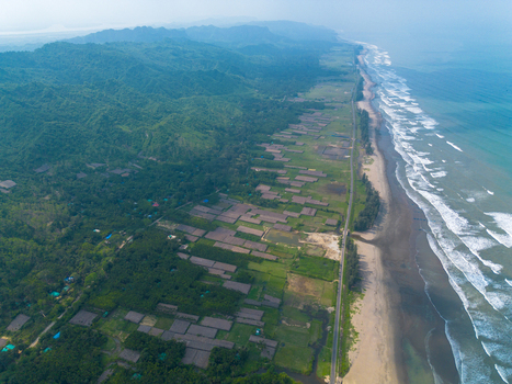 Aerial view of the long sandy coastline of Cox s Bazar beach with waves crashing on the shore next to lush green hills and a coastal road in Cox s Bazar Chittagong Division Bangladesh. Aerial view of the long sandy coastline of Cox s Bazar beach with waves crashing on the shore next to lush green hills and a coastal road in Cox s Bazar Chittagong Division Bangladesh.