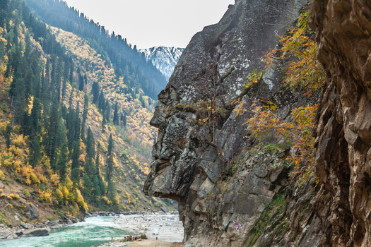 View of a rocky cliff resembling a human face overlooking the Neelum River and autumn colored forests in the valley Arang Kel Azad Kashmir Pakistan. View of a rocky cliff resembling a human face overlooking the Neelum River and autumn colored forests in the valley Arang Kel Azad Kashmir Pakistan.