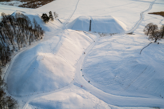 Aerial view of the Kernave Archaeological Site featuring snow covered hillforts and bare trees under soft winter light Kernave Vilnius County Lithuania.