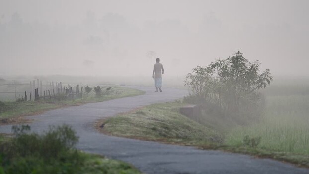 View of a man walking on a winding road in heavy fog Bangladesh.