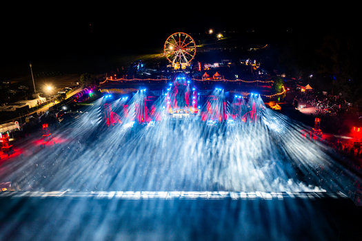 Herzogenaurach Germany 27 July 2025 Aerial view of the Open Beatz Festival at night featuring vibrant blue and red stage lights a large crowd and an illuminated Ferris wheel. Herzogenaurach Germany 27 July 2025 Aerial view of the Open Beatz Festival at night featuring vibrant blue and red stage lights a large crowd and an illuminated Ferris wheel.