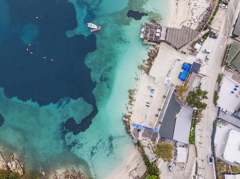 Aerial view of the turquoise waters and sandy beach of Ksamil with beach umbrellas a restaurant deck and a coastal road in Ksamil Vlore County Albania. Aerial view of the turquoise waters and sandy beach of Ksamil with beach umbrellas a restaurant deck and a coastal road in Ksamil Vlore County Albania.