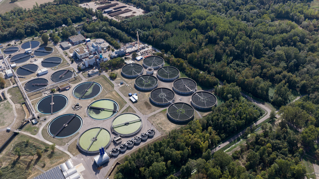 Aerial view of Klarwerk Karlsruhe featuring circular sedimentation tanks and industrial infrastructure surrounded by dense forest in Karlsruhe Baden Wurttemberg Germany.