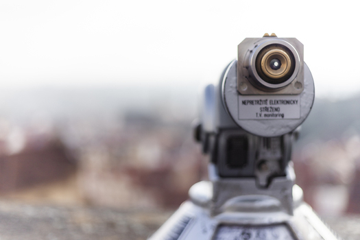 View of a tourist telescope eyepiece overlooking blurred historic rooftops and the city skyline in Prague Prague Czechia. View of a tourist telescope eyepiece overlooking blurred historic rooftops and the city skyline in Prague Prague Czechia.