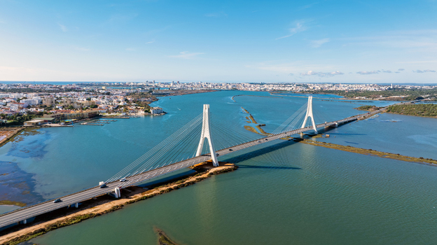 Aerial view of the cable stayed bridge spanning the Arade River with the city skyline in the background under a clear blue sky in Portimao Faro District Portugal. Aerial view of the cable stayed bridge spanning the Arade River with the city skyline in the background under a clear blue sky in Portimao Faro District Portugal.